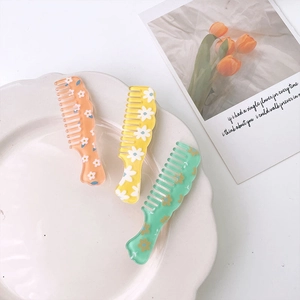 Set of colorful floral mini hair combs with daisy patterns in orange, yellow and green