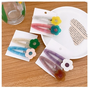 Close-up of acetic acid flower hair clips with marble texture on wooden tabletop background