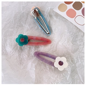 Detailed macro of acetate marble hair clips with colorful floral accents and metal grip