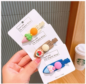 Detailed view of handmade cartoon cake and ice cream hair clips on packaging
