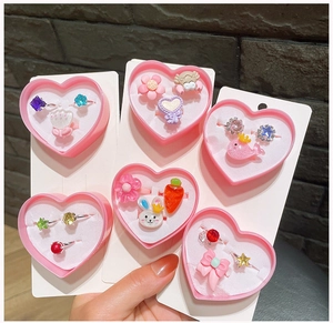 Close-up of pink heart boxes containing cartoon resin rings with animal and gem designs