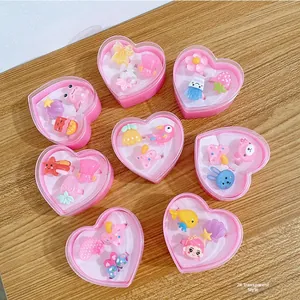 Close-up of pink heart-shaped boxes containing cute cartoon resin rings for girls