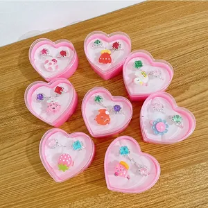 Detail view of pink heart-shaped gift boxes with various cute gemstone rings for kids
