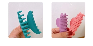 Detail of matte finish hair claw clips in dark green, mauve, and dusty pink shades