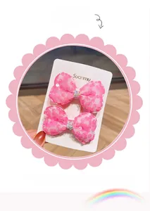 Dettaglio di due fermagli per capelli a fiocco con paillettes rosa e strass