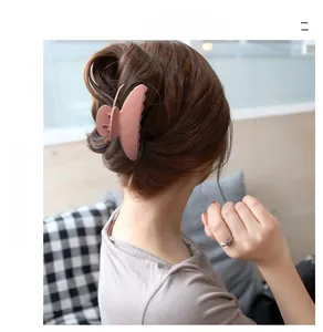 Close-up of a large matte pink hair claw clip securing a thick bun hairstyle