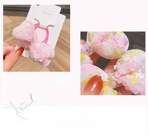 Dettaglio del fiocco rosa con paillettes, strass colorati ed elastico per capelli