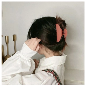 Detail of a large matte orange hair claw clip holding hair in an elegant updo