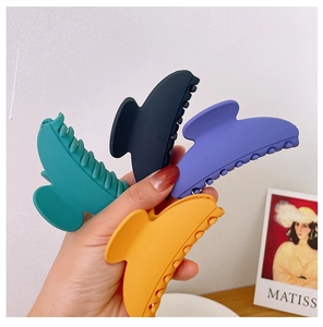 Detailed close-up of matte geometric hair claws in various colors held by hand