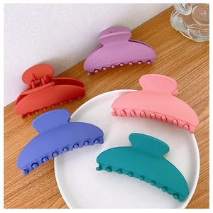 Matte finish hair claw clips in assorted pastel colors on a rustic wooden table surface