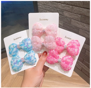 Dettaglio di fermagli per capelli con fiocchi di paillettes in rosa e azzurro