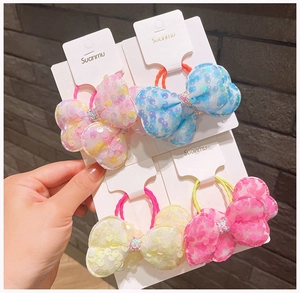 Dettaglio di quattro elastici per capelli con fiocchi di paillettes in vari colori