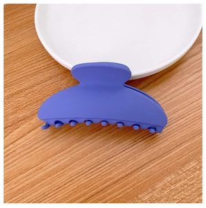 Close-up of matte dark blue geometric hair claw clip on a white decorative porcelain plate