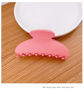 Detailed close-up of a matte pink geometric claw clip on a white ceramic tray