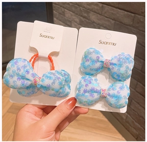 Dettaglio di fermagli a fiocco con paillettes azzurre e elastico su cartoncino