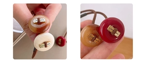 Detail showing high-elastic hair tie with amber resin bead and LOVE DAYS metal plate
