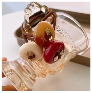 Close-up of three elastic hair ties with resin beads and gold Lovays metal square accents