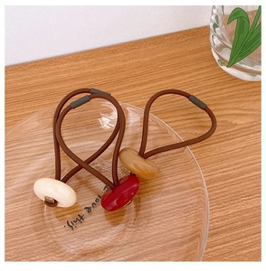 Close-up of three elastic hair ties with oval resin beads in cream, burgundy, and amber