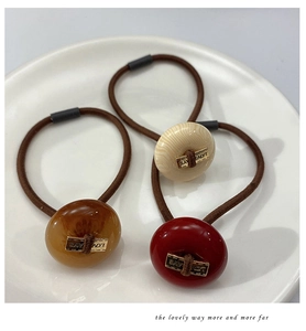 Detailed view of high-elasticity hair ties with polished round button charms in three colors