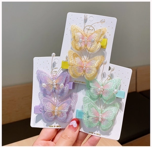 Détail de pinces à cheveux papillon brodées avec perles sur carte de présentation
