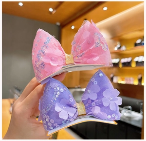 Vue détaillée des barrettes nœuds à paillettes roses et mauves avec fleurs en tulle