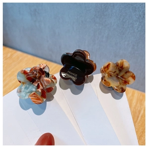 Detailed macro view of handmade acetate flower hair claws with elegant marble patterns