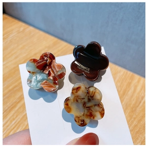 Detailed view of three mini floral hair claws in solid brown, tortoise, and marble texture