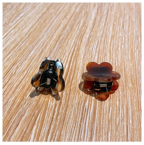 Close-up of tortoise shell and black-white spotted floral hair clips on wood surface