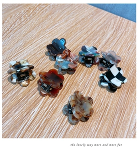 Flat lay of small floral claw clips in assorted marble, shell, and checkered patterns