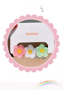 Détail de trois mini pinces à cheveux fleuries rose, blanc et vert sur une carte support