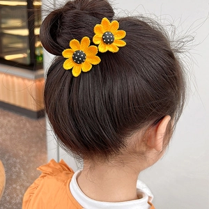 Détail d'accessoires de cheveux tournesol au crochet faits main sur un chignon enfant