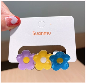 Gros plan de trois pinces à cheveux fleurs en acrylique coloré sur carte pour fillettes