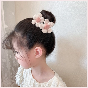 Détail d'une barrette à fleurs tricotées roses sur un chignon pour enfant