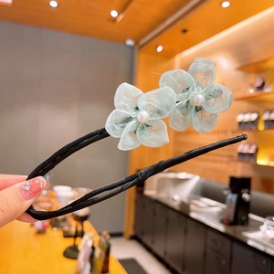 Détail d'un accessoire chignon avec fleurs en gaze vert menthe et perles blanches
