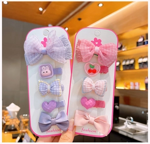 Dettaglio del set di 10 fermagli per capelli da bambina con fiocchi e decorazioni rosa