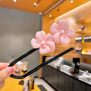 Détail de fleurs en tissu rose et perles blanches sur un pic à cheveux noir en forme de U