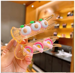 Dettaglio ravvicinato di fermagli per capelli con pesche e arcobaleno per bambine