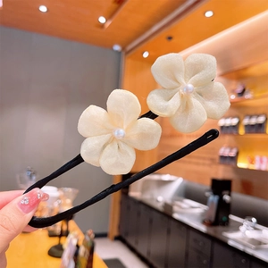 Détail d'une pince à cheveux de style coréen avec fleurs en tissu blanc et perles en main
