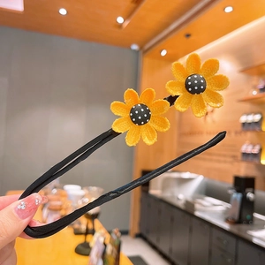 Détail de l'épingle à cheveux noire en U avec tournesols au crochet et pois centraux