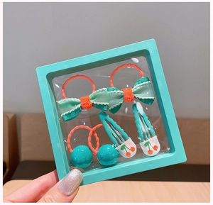 Close-up of mint green bow hair ties and cherry print clips in a square display frame