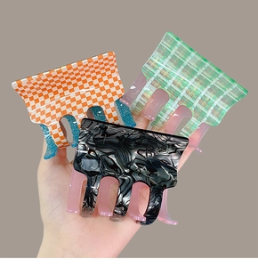 Close-up of acetate hair claws in orange checkerboard and green plaid patterns