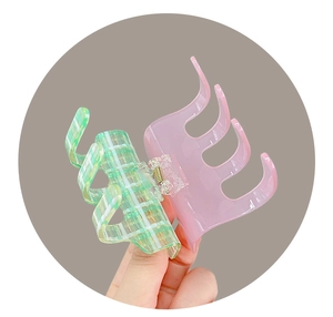 Detail of checkered green and translucent pink acetate hair claw with metal spring