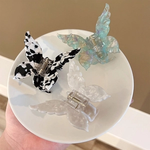 Three acetate butterfly hair clips in cow print, pearly white and blue-green colors
