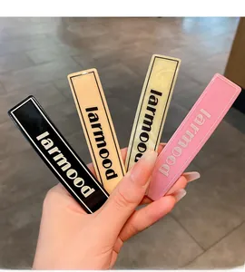 Detail of four acrylic rectangular hair clips in black, beige, yellow and pink colors