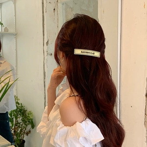 Close-up of a French vintage cream hair clip with black lettering on long brown hair