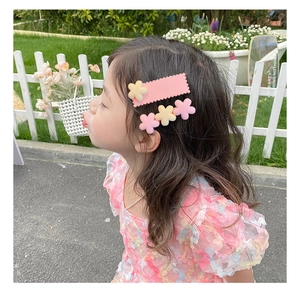 Détail de barrettes à fleurs aux couleurs pastel portées par une petite fille dehors