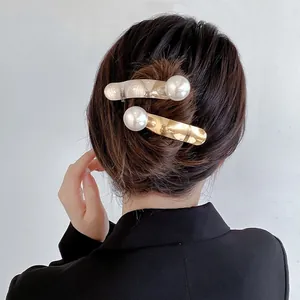 Détail de grandes perles sur pinces à cheveux or et argent dans un chignon