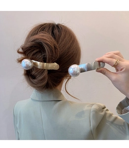 Gros plan de pinces à cheveux élégantes en or et argent avec de grandes perles blanches