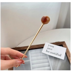 Close-up of golden hair stick with a polished coffee-colored resin bead ornament