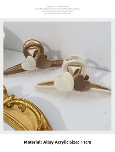 Detail view of large 11cm heart hair clips in milk tea and cream colors with metal springs